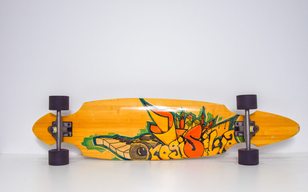 Wooden skateboard on its side, bottom on display, with bright graphics decorating the bottoms surface.