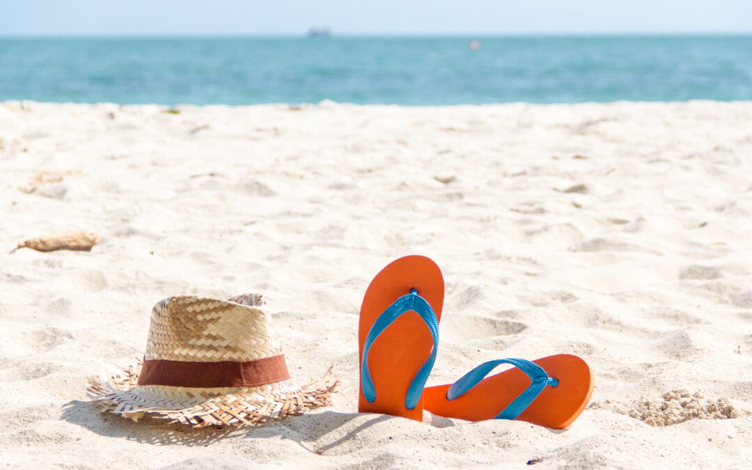 flip-flop and a woven hat on the sand beach.